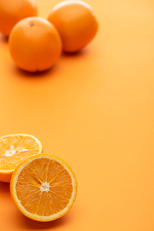 selective focus of ripe juicy whole and cut oranges on colorful background