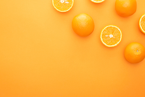 top view of ripe juicy whole oranges and slices on colorful background