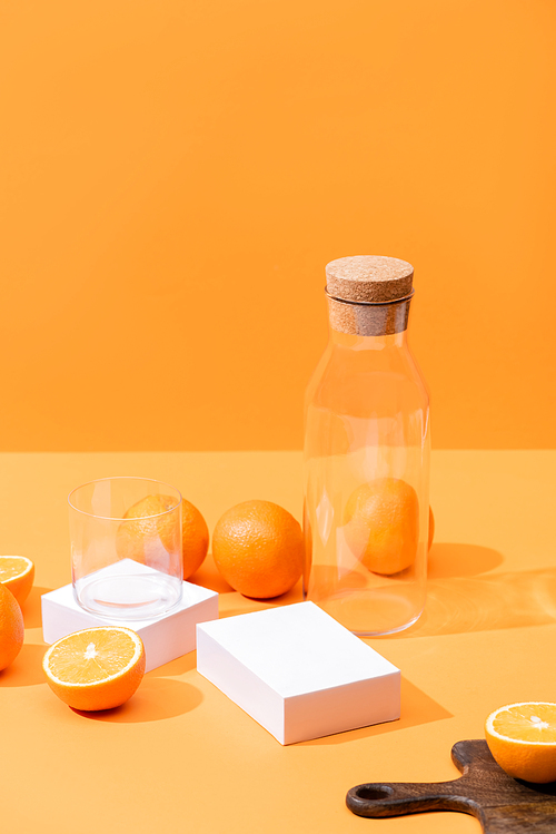 fresh orange juice in glass and bottle near ripe oranges, wooden cutting board isolated on orange