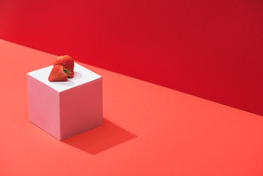 fresh ripe strawberry on cube on red background