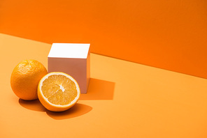 fresh oranges and white cube on orange background