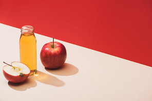 fresh juice in bottle near apples on red background