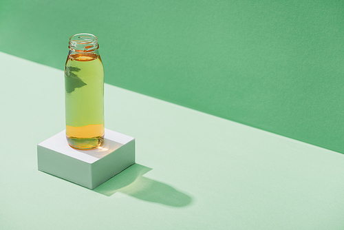 fresh apple juice on white cube on green and turquoise background