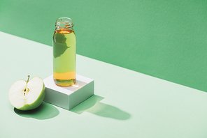 fresh juice near apple half and and white cube on green and turquoise background