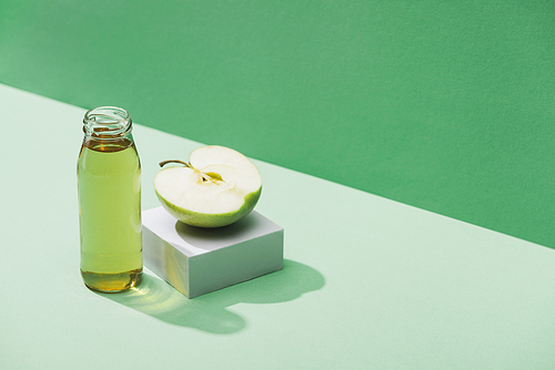 fresh juice near apple half and and white cube on green and turquoise background