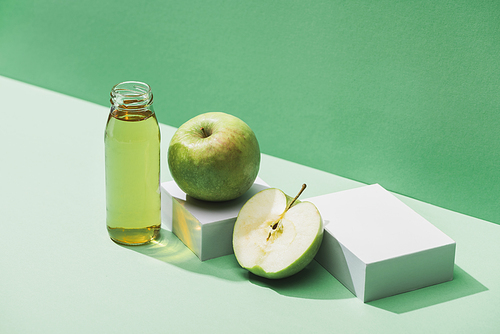 fresh juice near apples and and white cubes on green and turquoise background