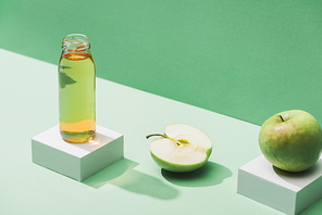 fresh juice near apples and and white cubes on green and turquoise background