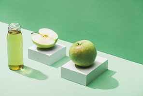 fresh juice near apples and and white cubes on green and turquoise background