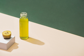 fresh juice near kiwi and and white cube on green and white background