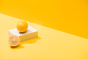 fresh lemons and white cube on yellow background