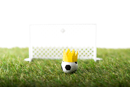 selective focus of toy football gates and ball with paper crown on green grass isolated on white, sports betting concept