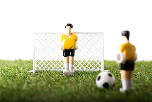 selective focus of toy football players, gates and ball on green grass isolated on white, sports betting concept