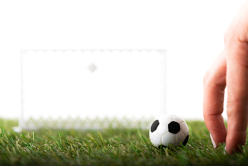 cropped view of female fingers near toy football gates and ball on green field isolated on white, sports betting concept