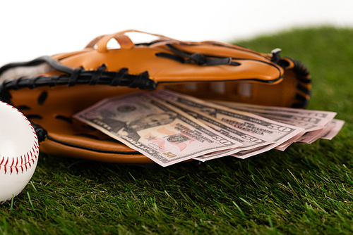 selective focus of dollar banknotes in baseball glove on green grass isolated on white, sports betting concept