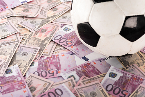 close up view of soccer ball on euro and dollar banknotes, sports betting concept