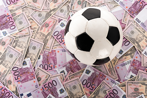 top view of soccer ball on euro and dollar banknotes, sports betting concept