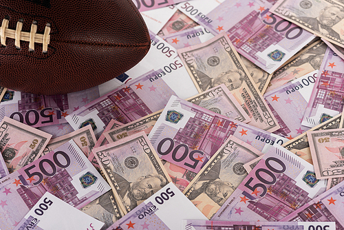 rugby ball on euro and dollar banknotes, sports betting concept