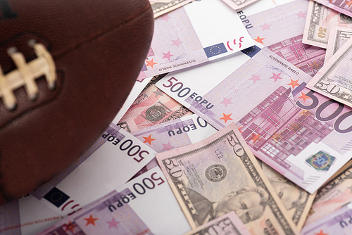 selective focus of rugby ball on euro and dollar banknotes, sports betting concept