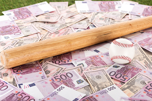 selective focus of baseball bat and ball on euro and dollar banknotes, sports betting concept