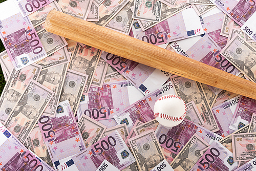 top view of baseball bat and ball on euro and dollar banknotes, sports betting concept