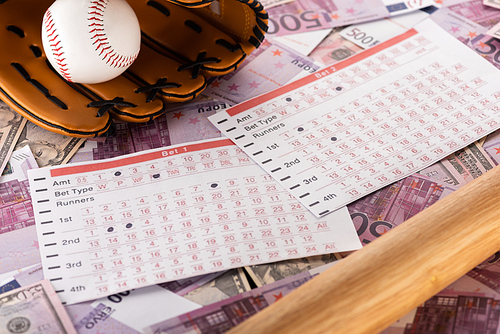 betting lists near baseball bat, glove and ball on euro and dollar banknotes, sports betting concept