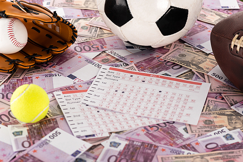 baseball glove and ball, soccer, tennis and rugby balls near betting lists on euro and dollar banknotes, sports betting concept