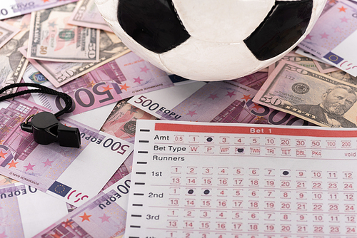 soccer ball, whistle and betting list on euro and dollar banknotes, sports betting concept