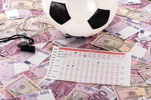 soccer ball, whistle and betting list on euro and dollar banknotes, sports betting concept