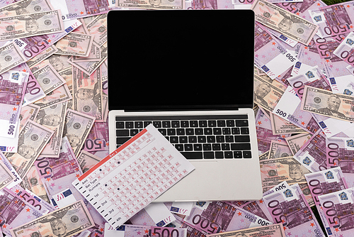 laptop with blank screen and betting list on euro and dollar banknotes, sports betting concept