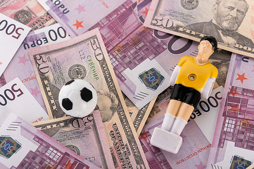toy soccer ball and football player on euro and dollar banknotes, sports betting concept