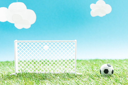 toy football gates and ball on green grass on blue background with clouds, sports betting concept