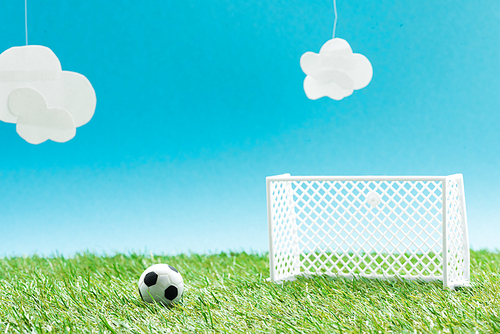football field with miniature soccer ball and gates on blue background with clouds, sports betting concept