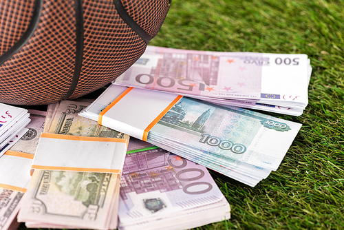 close up view of baseball ball near dollar and euro banknotes on green grass, sports betting concept