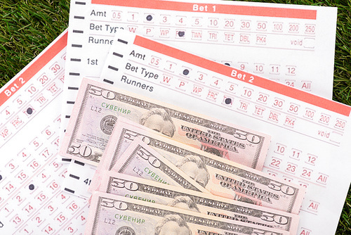 dollar banknotes and betting lists on green grass, sports betting concept