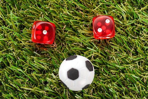 dice and toy soccer ball on green grass, sports betting concept