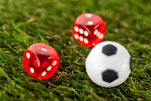 selective focus of dice and toy soccer ball on green grass, sports betting concept