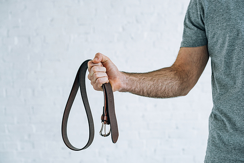 cropped view of man holding leather belt at home