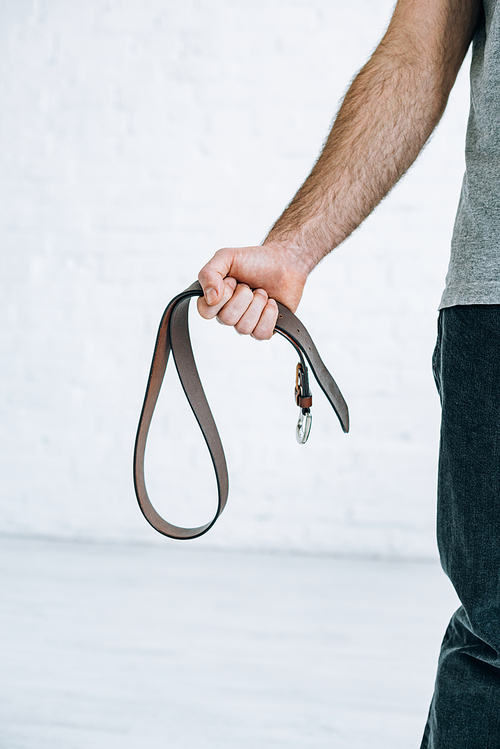 cropped view of man holding leather belt at home