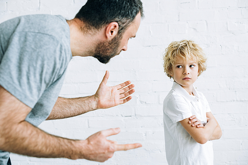 partial view of bearded father scolding son at home