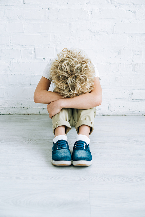 upset preteen boy sitting on floor at home