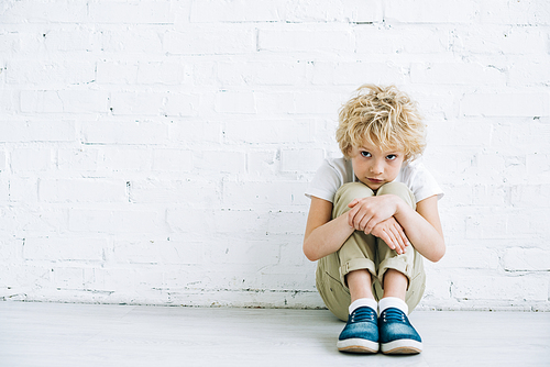 upset preteen boy sitting on floor at home