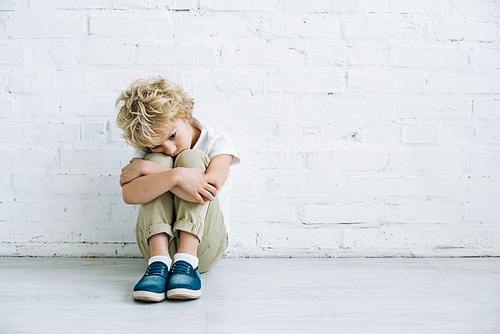 upset preteen boy sitting on floor at home