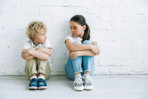 upset sister and brother sitting on floor at home