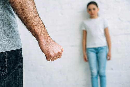 partial view of abusive father and scared daughter at home