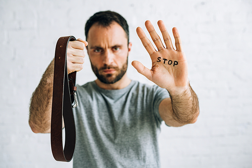 selective focus of father showing belt and inscription stop on palm