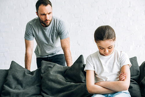bearded father and sad daughter sitting on sofa having conflict