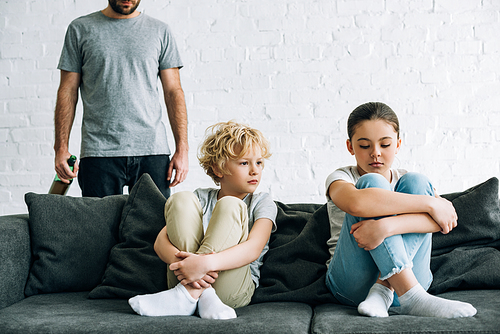 cropped view of alcohol addicted father with beer and upset children on sofa