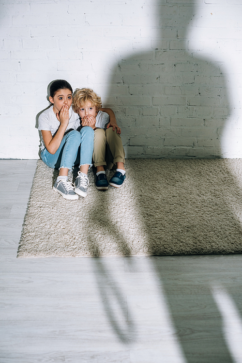 big silhouette and scared children sitting on carpet