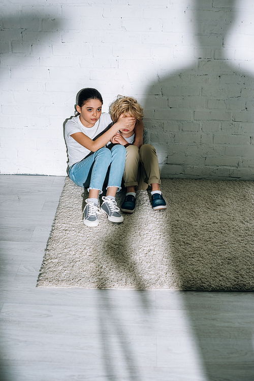 big silhouette and scared children sitting on carpet