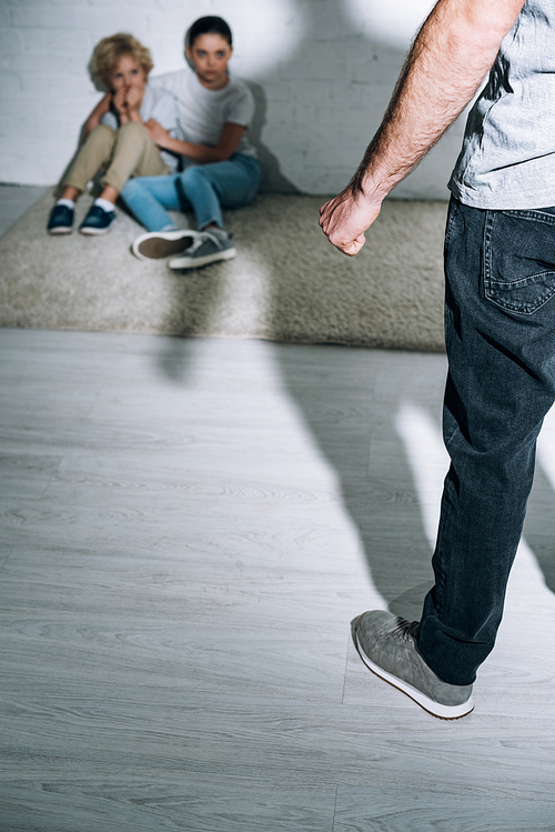 cropped view of father and scared children sitting on carpet